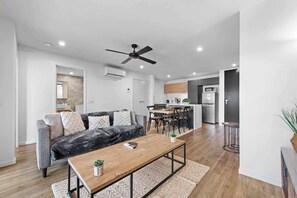 A modern living room with a sofa, coffee table, and dining area. - Stylish & Slick! 1bed/1bath/1car ~ Walk to CBD (Brisbane)