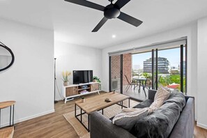Ein modernes Wohnzimmer mit Flachbildfernseher, einer Couch, einem Couchtisch und einem Essbereich mit Tisch und Stühlen.
