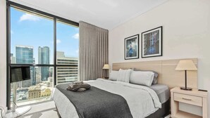 A hotel room with a large window, a bed, a bedside table, and a wall-mounted TV. - City Centre! 1bed/1bath/study/1car/balcony ~ CBD (Brisbane)