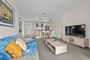 Ein modernes Wohnzimmer mit Sofa, Couchtisch, Fernseher und einem Essbereich mit Stühlen und Tisch.