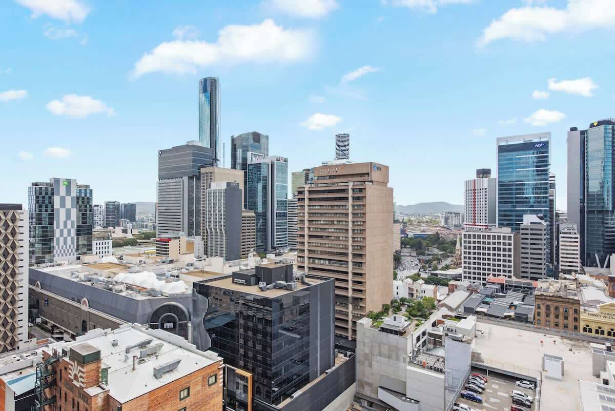 A cityscape with modern high-rise buildings, a mix of architectural styles, and a clear sky.