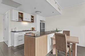 Eine moderne Küche mit weißen Schränken, einer zentralen Kücheninsel und einem Essbereich mit Tisch und Stühlen.