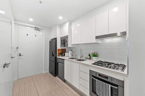 A modern kitchen with white cabinets, a stainless steel range, a microwave, and a dishwasher. - Infinity Excellence!~1bed/1bath/office/1car~views! (Brisbane)