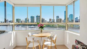 Ein Zimmer mit Blick auf die Stadt, ein runder Tisch mit Stühlen und eine Vase mit Blumen.