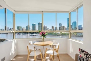 Ein Zimmer mit Blick auf die Stadt, ein runder Tisch mit Stühlen und eine Vase mit Blumen.