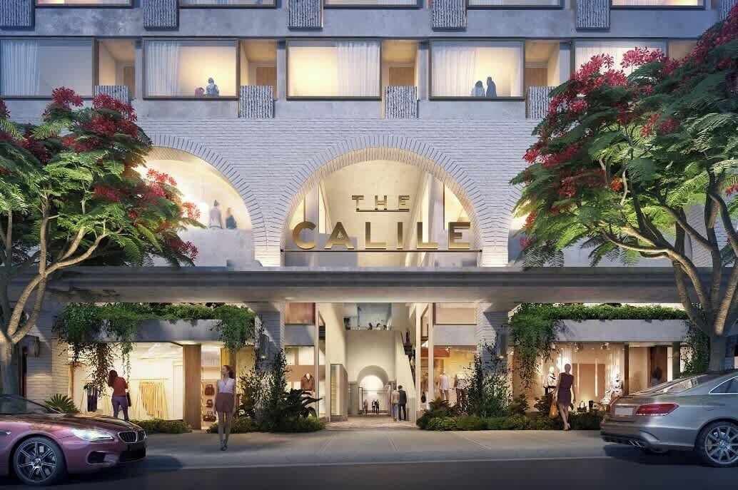 Entrada de hotel con un letrero llamativo, ventanas arqueadas y un vestíbulo cubierto.