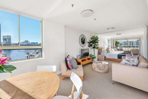 Eine moderne Wohnung mit Essbereich, Wohnzimmer und Schlafzimmer, mit einem großen Fenster und Blick auf die Stadt.