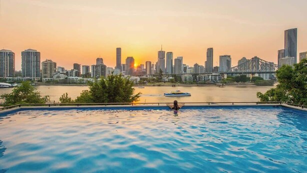 Ein Schwimmbad mit Stadtansicht und einer Brücke im Hintergrund.