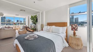 Ein modernes Schlafzimmer mit einem großen Bett, Blick auf die Stadt und einem Balkon.