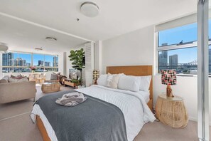 Ein modernes Schlafzimmer mit einem großen Bett, Blick auf die Stadt und einem Balkon.