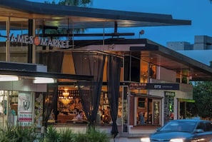 Ein modernes Gebäude mit Glasfassade, einem einsehbaren Restaurant im Inneren und einem geparkten Auto vor der Tür.