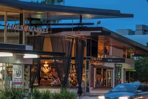 Ein modernes Gebäude mit Glasfassade, einem einsehbaren Restaurant im Inneren und einem geparkten Auto vor der Tür.