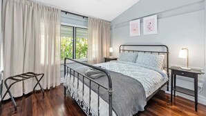 A bedroom with a bed, a nightstand, a lamp, a ceiling fan, and a window with curtains. - The Office! 1 Bed/1 Bath ~ New Farm (Brisbane)