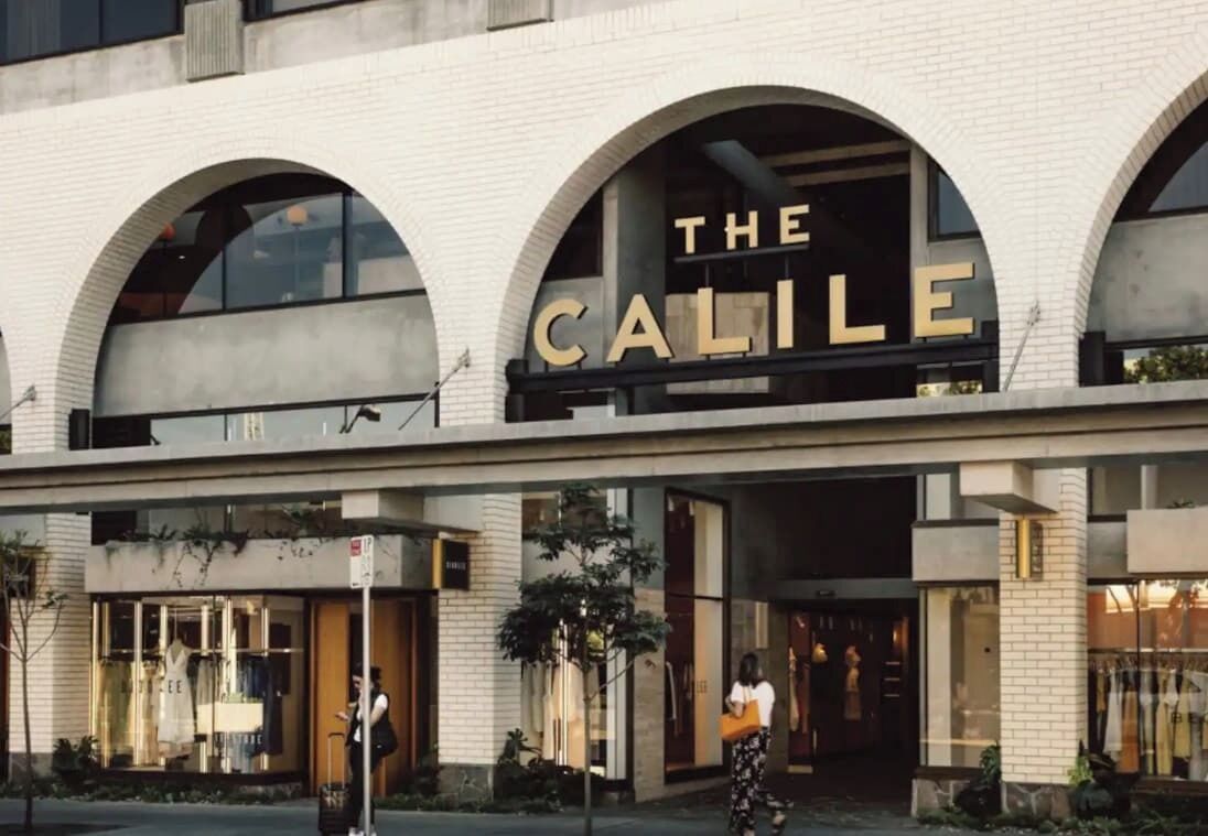 Un bâtiment portant l’inscription « THE CALILE », doté de grandes fenêtres et d’une façade en briques.