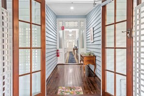 A hallway with wooden flooring, a welcome mat, and a door leading to a room. - The Fireplace! 1 Bed/1 Bath/1 Car ~ New Farm (Brisbane)