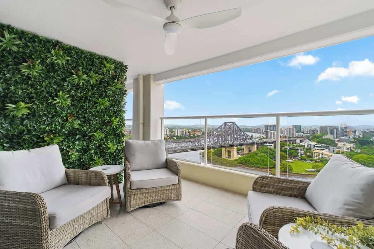 A balcony with wicker furniture, a green wall, and a city view.