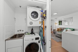 A compact laundry room with a washing machine, dryer, and ironing station. - Stunning! 2bed, 1bath, 1car, Views ~ CBD (Brisbane)