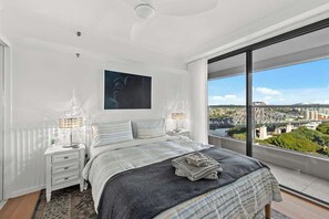 A bedroom with a large bed, a nightstand, a lamp, and a view of a cityscape. - Stunning! 2bed, 1bath, 1car, Views ~ CBD (Brisbane)