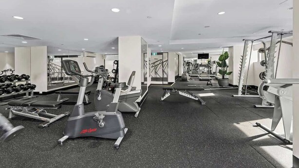 Ein Fitnessstudio mit Cardiogeräten, Krafttrainingsgeräten und Kurzhanteln.