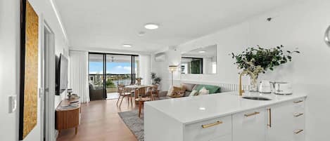 A modern kitchen with a central island, a dining area with a view, and a living space with a large window.