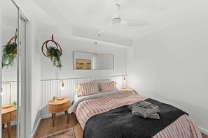 A bedroom with a bed, bedside tables, a ceiling fan, a mirror, and a window. - Stunning! 2bed, 1bath, 1car, Views ~ CBD (Brisbane)