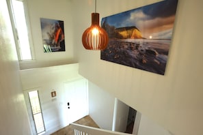 Eine Treppe mit Blick auf eine Strandlandschaft und einem Sonnenuntergangsgemälde an der Wand.