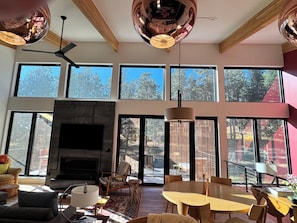 A spacious living room with a fireplace, large windows, and a dining area. - Stylish, modern living on 2.5 acres near Denver. (Morrison)