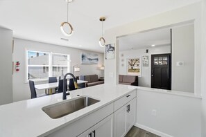 A modern kitchen with a central island, a dining area with a table and chairs, and a living area with a sofa and a coffee table. - Cozy 3BR Home Close to WSU, UD & Wright-Patt AFB (Dayton)