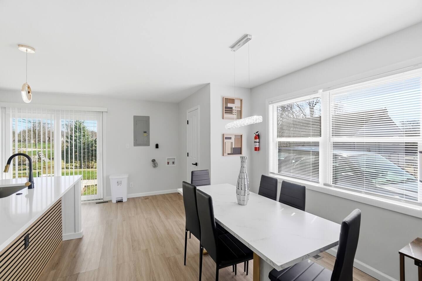 Une cuisine moderne avec un plan de travail blanc, des chaises noires et une table à manger.