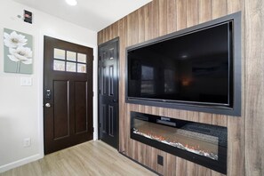 Ein Flur mit einer dunklen Holztür, einem wandmontierten Flachbildfernseher und einem eingebauten Kamin.