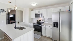 A modern kitchen with white cabinetry, stainless steel appliances, and pendant lighting. - Cozy 3BR Home Close to WSU, UD & Wright-Patt AFB (Dayton)