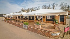 A row of brick buildings with white awnings, each with a sign indicating a restaurant. - Tewin Bury Farm Hotel (Welwyn)
