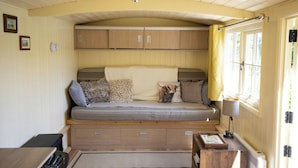 A cozy room with a built-in sofa, wooden cabinets, a small table with a lamp, and a window with curtains. - Tewin Bury Farm Hotel (Welwyn)
