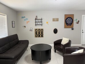 Ein Wohnzimmer mit einem schwarzen Sofa, einem runden schwarzen Couchtisch und einem braunen Ledersessel.