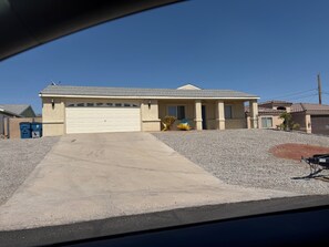 A single-story house with a garage, a driveway, and a small front yard with landscaping. - Lake Havasu Getaway- Private Pool-4BR -Sleeps 10- Family Fun (Lake Havasu City)