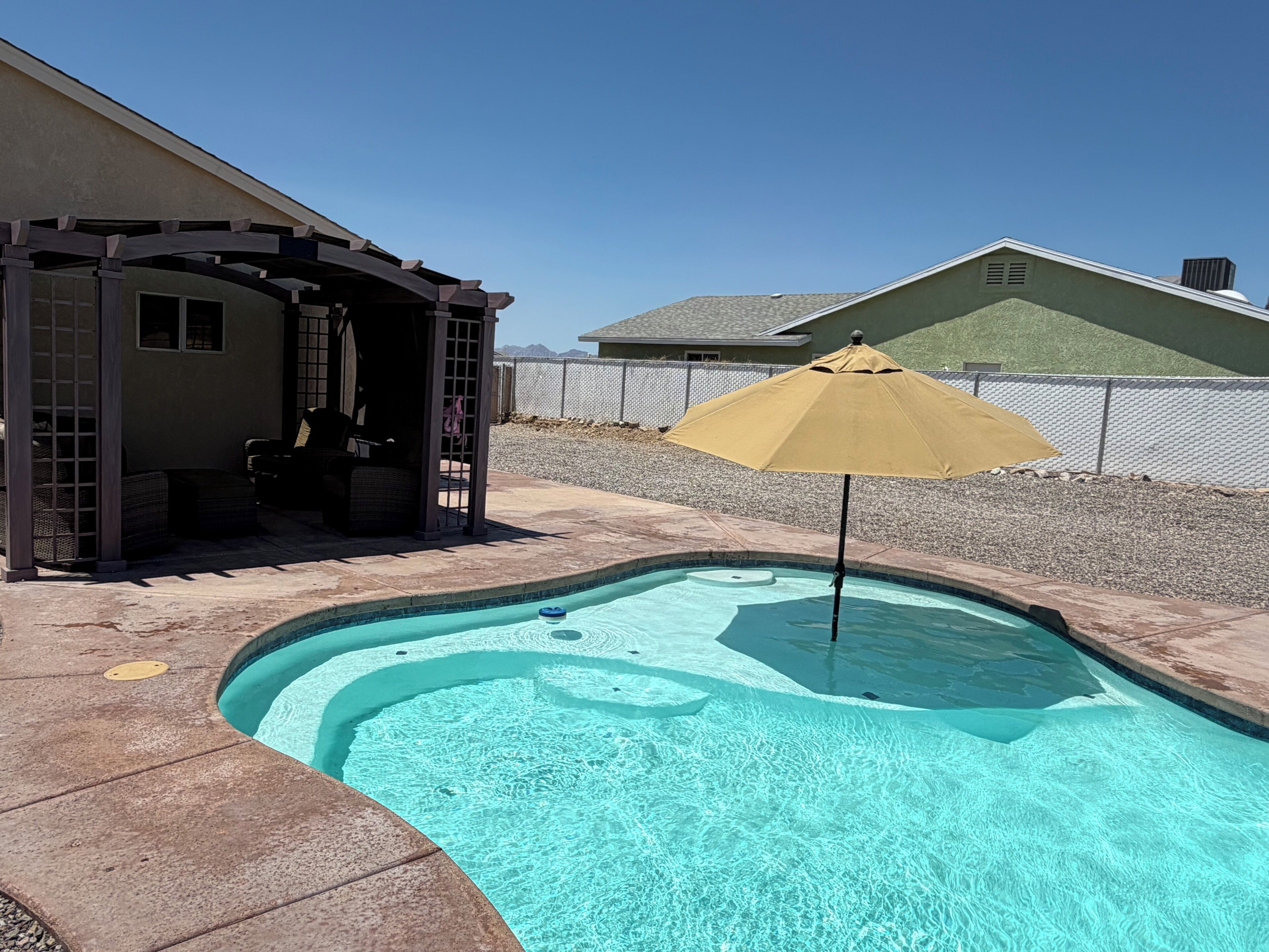 A swimming pool with a hot tub and a covered seating area.