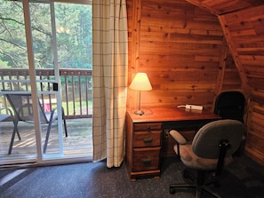 A wooden cabin with a desk, chair, and a lamp. There is a sliding glass door leading to an outdoor deck. - Updated cabin on the Au Sable River 10 minutes from Grayling (Grayling)