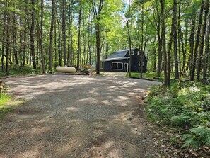 Une zone boisée avec une allée de gravier menant à un chalet.