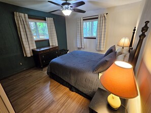 A bedroom with a bed, a nightstand, a lamp, a dresser, and a ceiling fan. - Updated cabin on the Au Sable River 10 minutes from Grayling (Grayling)