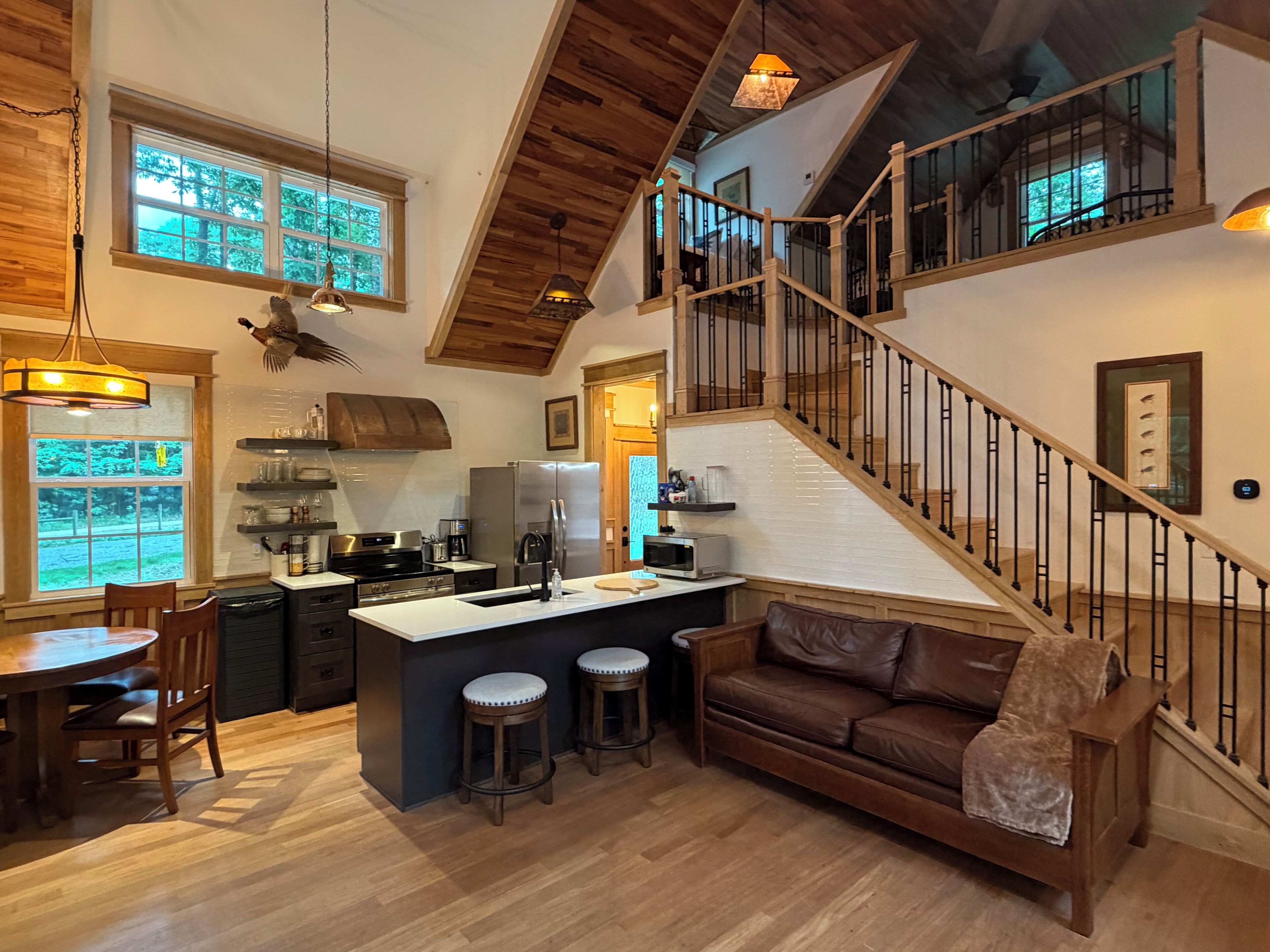 A spacious kitchen with a central island, wooden flooring, and a staircase leading to an upper level.