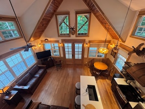 A spacious loft with high ceilings, large windows, a dining area, a kitchen, and a seating area with a fireplace.