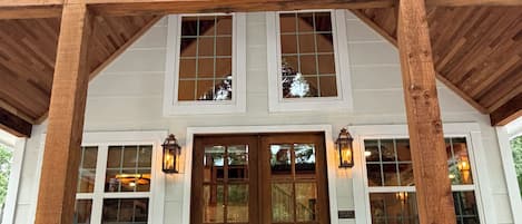 A wooden porch with a railing, a staircase leading to a door, and a view of the building's interior.