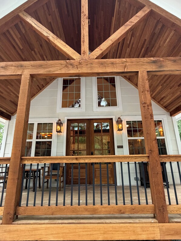A wooden porch with a railing, a staircase leading to a door, and a view of the building's interior.