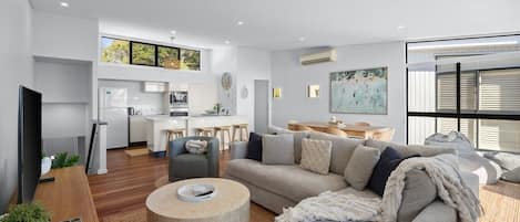 A modern living space with a sofa, coffee table, and a kitchen area in the background.