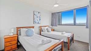 A hotel room with two single beds, a ceiling fan, a window with curtains, and a painting on the wall. - Water Views at Pacific Keys Central - Hosted By Gold Coast Holiday Stays (Mermaid Waters)