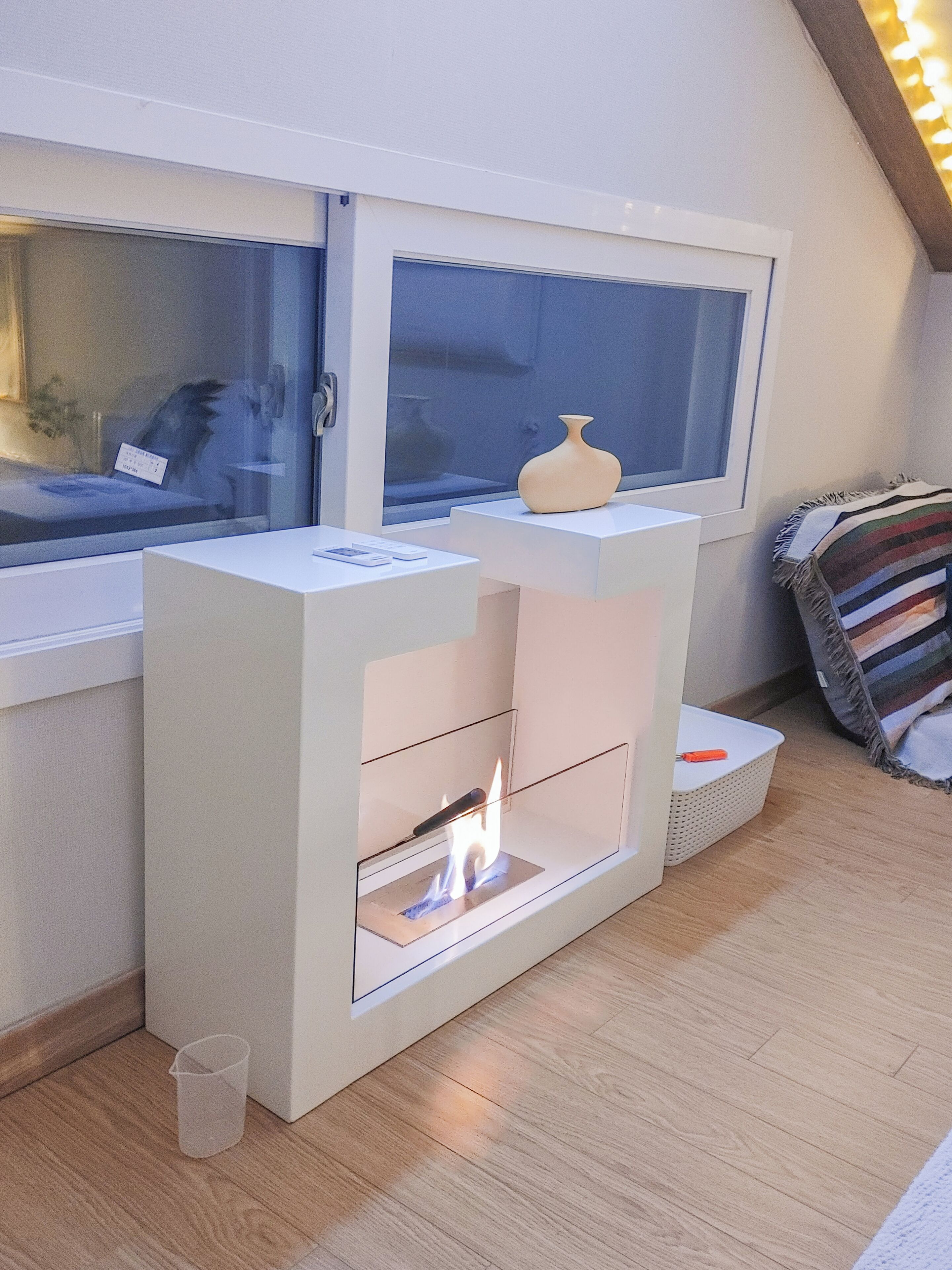 Een moderne kamer met een open haard, een raam en een gestreepte deken.