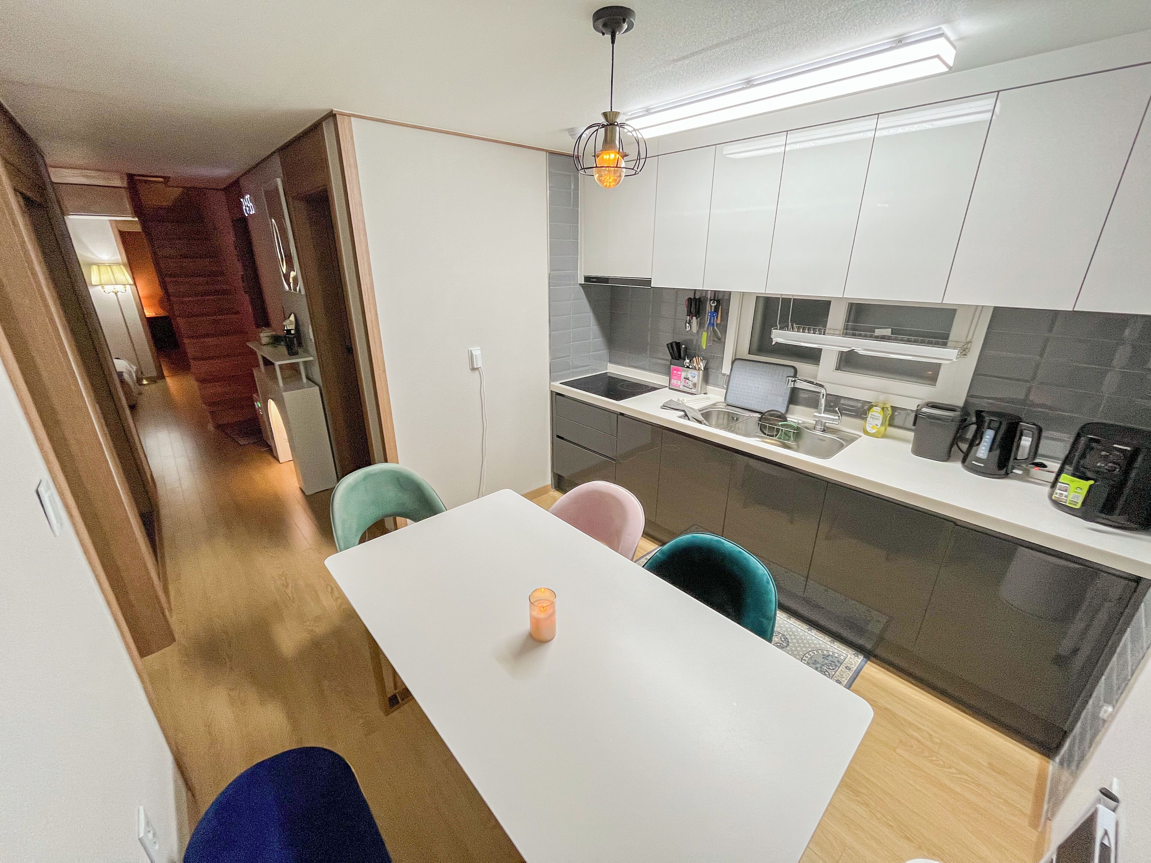 Een kleine keuken met een eethoek, met een witte tafel, stoelen en een kaarsje.