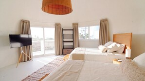 Een slaapkamer met een bed, een televisie, een raam en een plafondlamp.