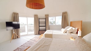 A bedroom with a bed, a TV, a window, and a ceiling light.