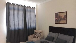 Une chambre à coucher avec un lit, une chaise, une table de chevet et un tableau au mur.